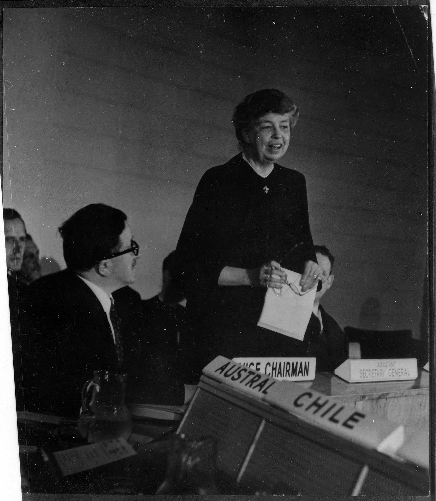 Photo of Eleanor Roosevelt speaking at the United Nations to other UN delegates. Seated next to her are delegates from Australia and Chile.