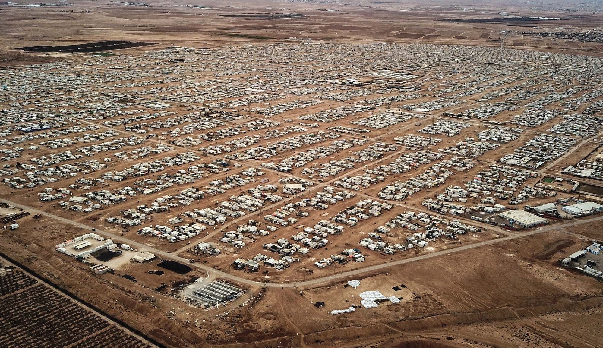 Aerial view of a vast refugee camp with roads and thousands of buildings and tents.