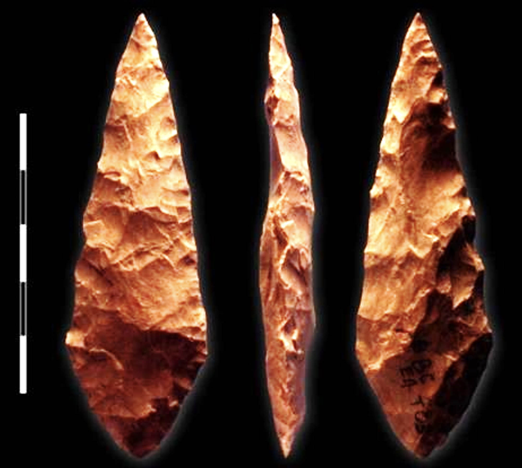 Three flaked point stone tools against a black background.