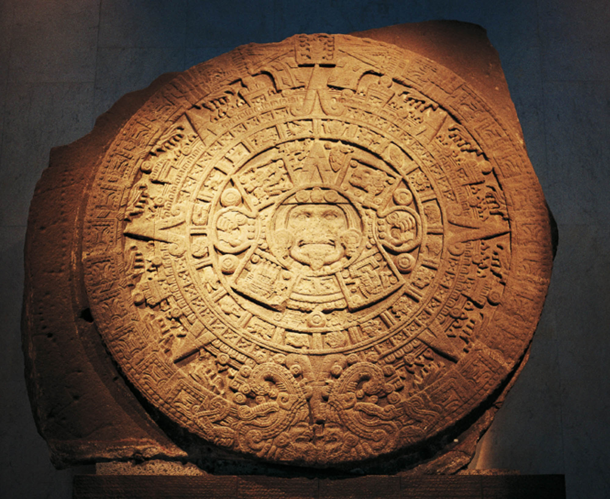 Large Aztec calendar stone with carvings on it.