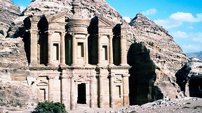 Photo of a monumental building carved out of rock with a blue sky in the background.