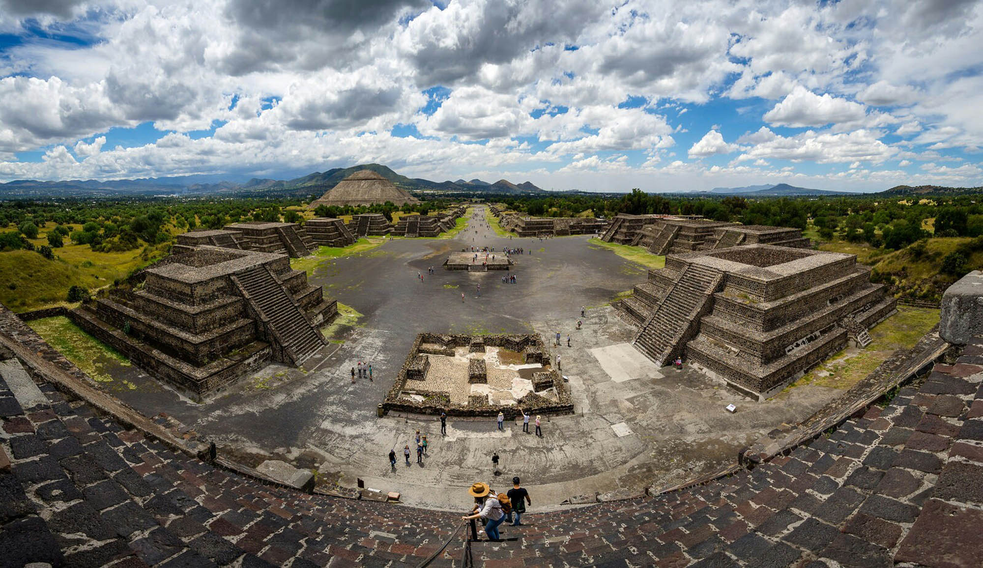 Panoramic view of a Mesoamerican plaza with central plaza and several pyramids.  