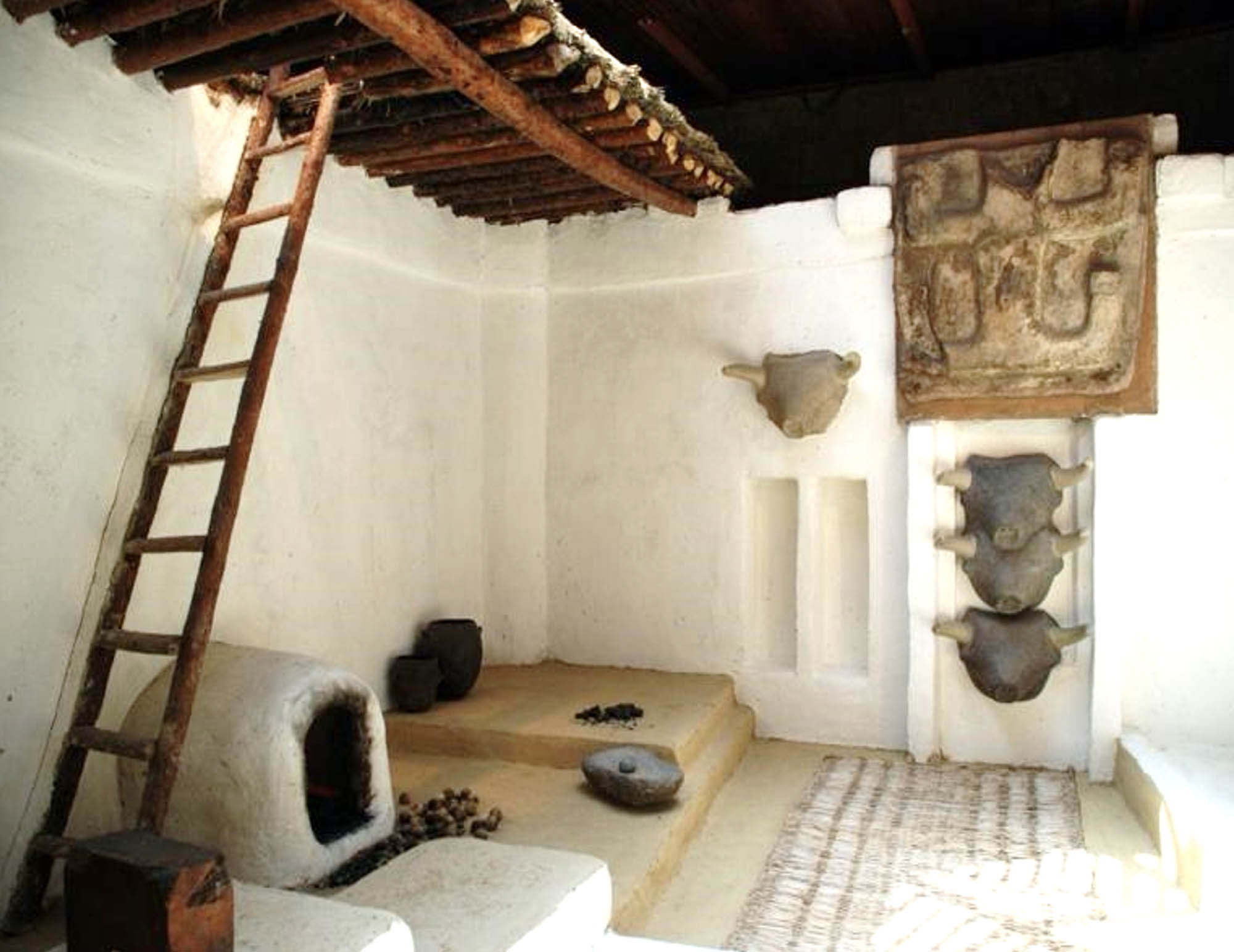 Interior living quarter featuring a ladder to an upper level sleeping platform, wood burning fireplace, and decorative wall art.