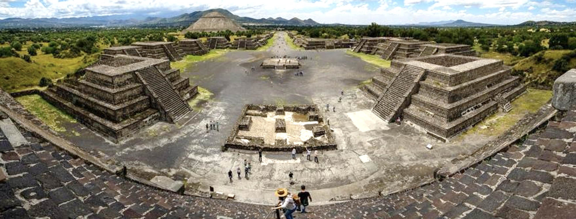 Panoramic view of a Mesoamerican plaza with central plaza and several pyramids.