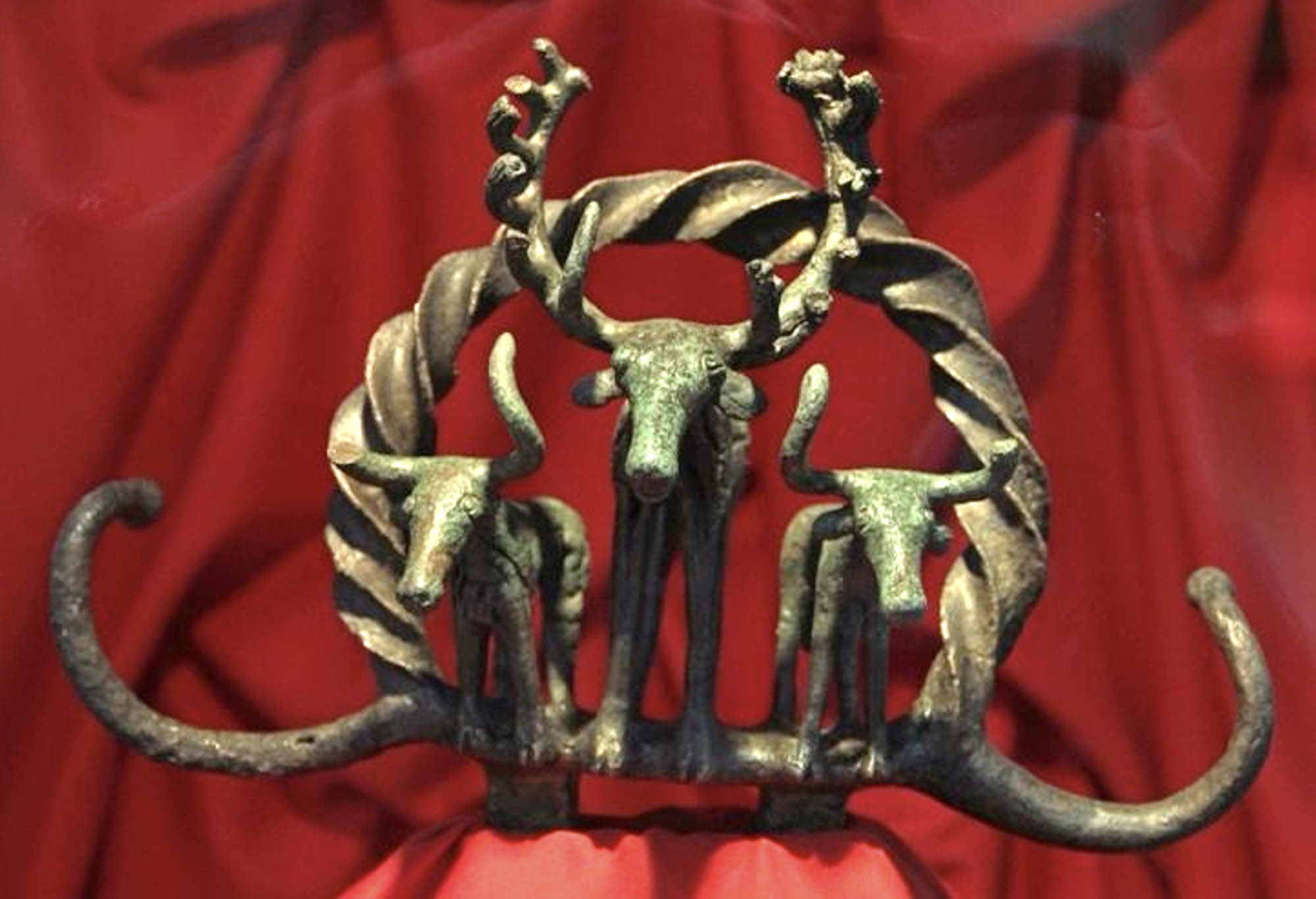 Bronze sculpture three cattle with long horns, framed by a decorative wreath.