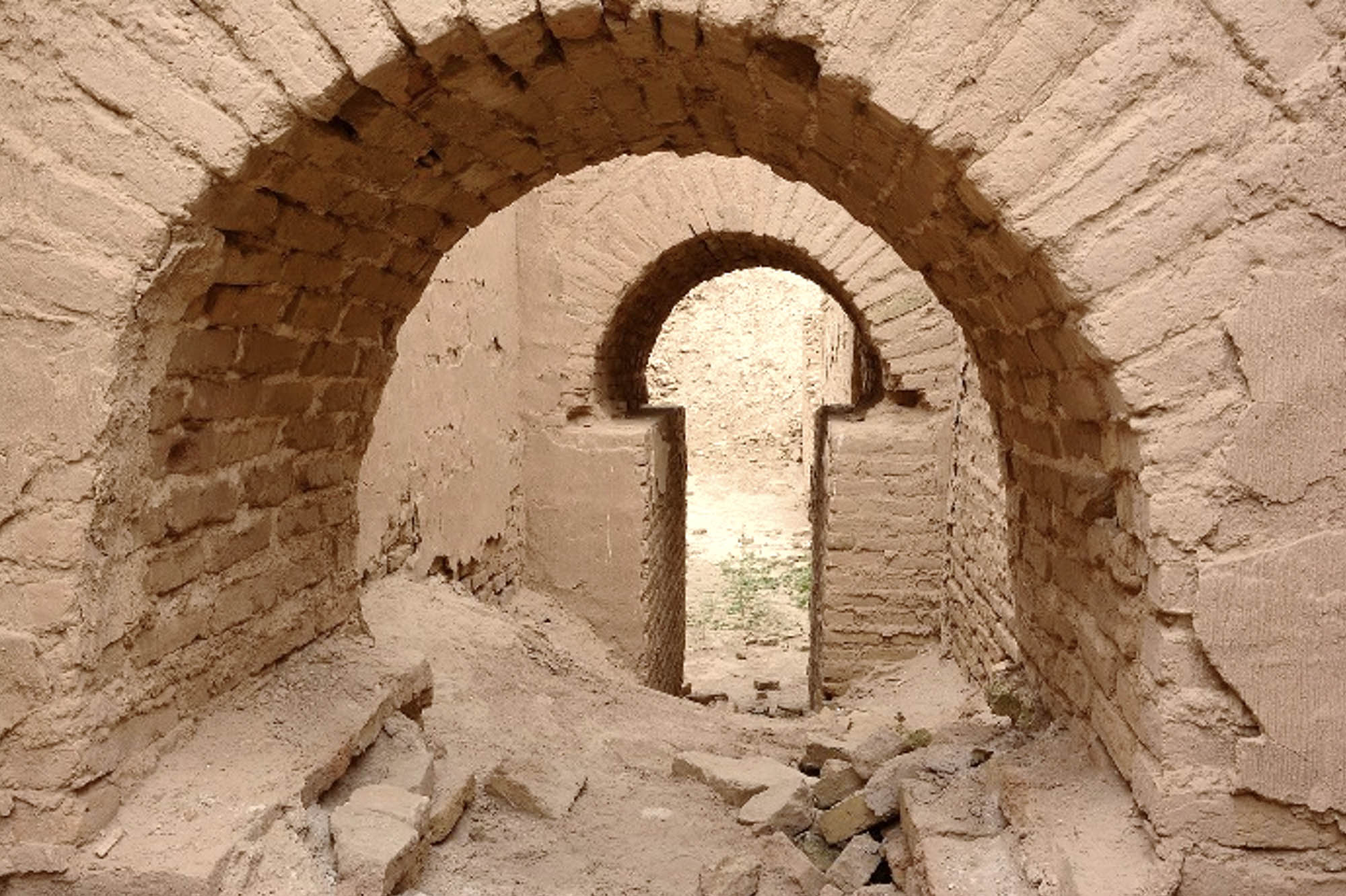 Inside a ruined temple looking towards two stone arches.