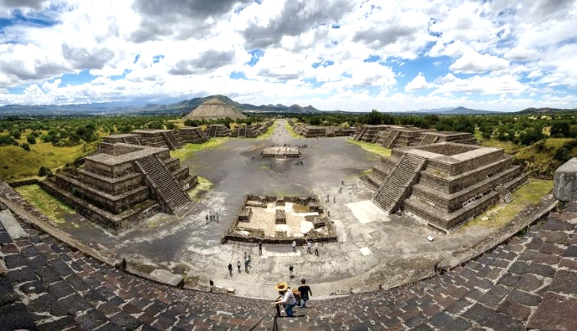 Panoramic view of a Mesoamerican plaza with central plaza and several pyramids.
