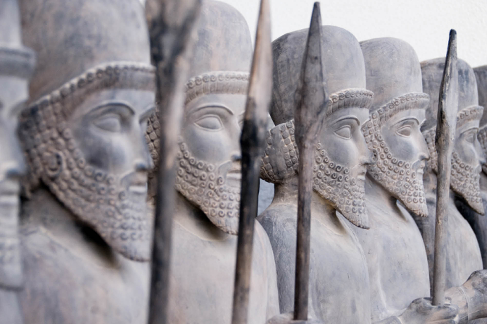 A photograph of a line of statues. The statues are guard-like, mostly identical, holding spears.