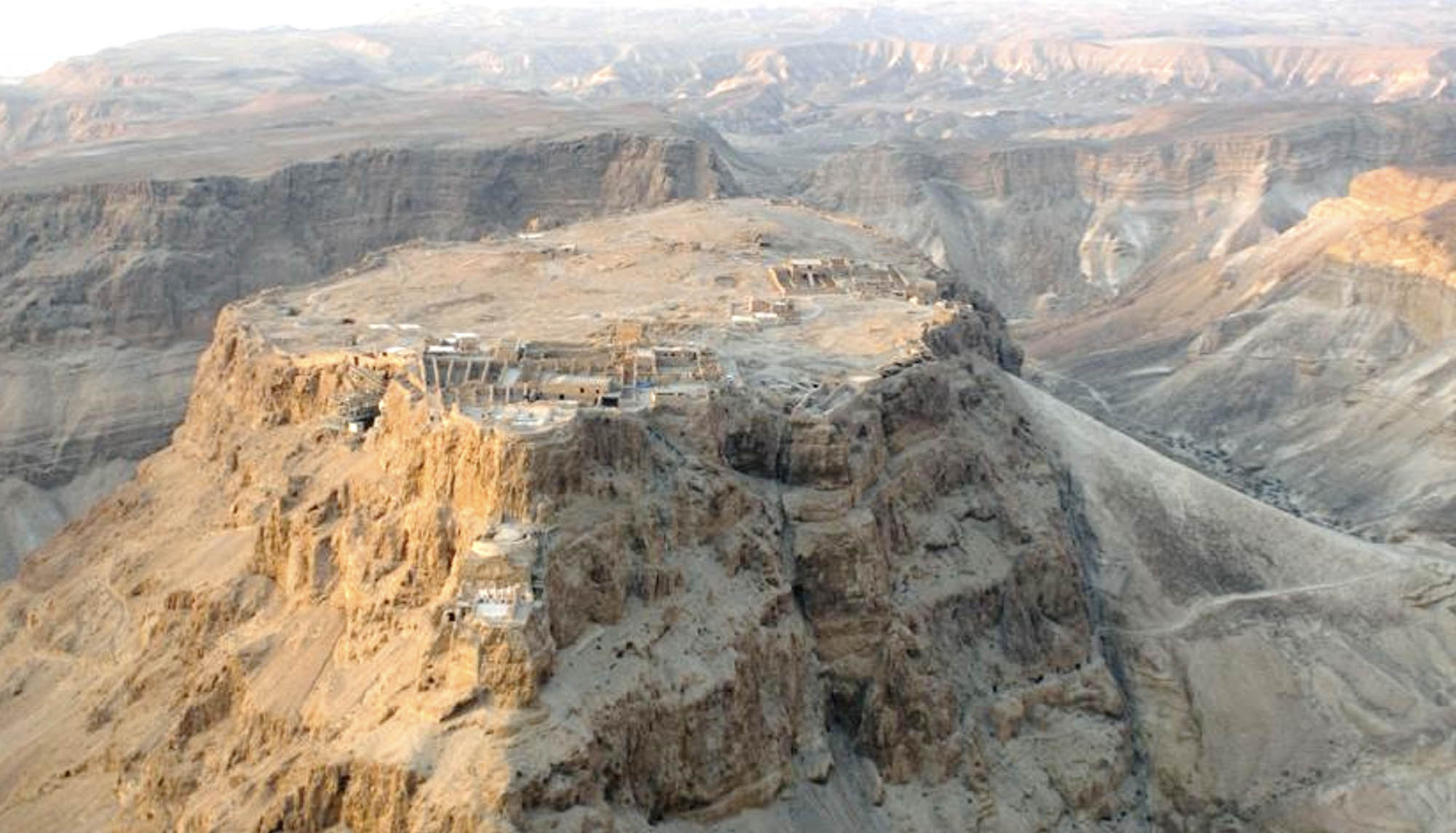 Birds-eye view of a rocky, mountainous area. The site is on top of a large rock formation with a flat top.