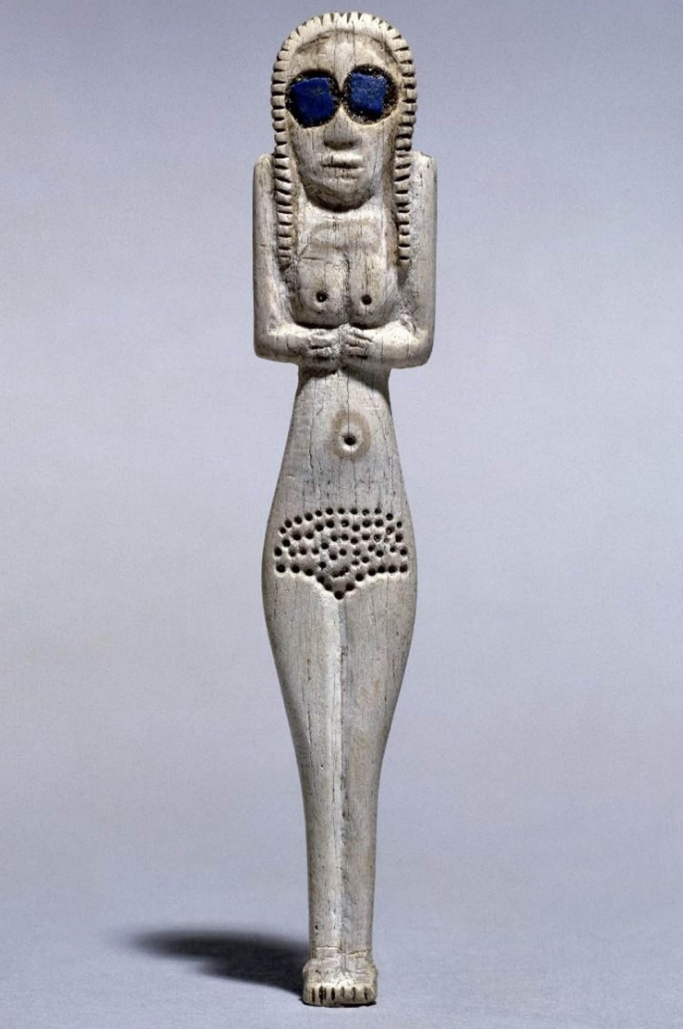 A figure of a woman carved out of bone, with large blue stones for eyes.