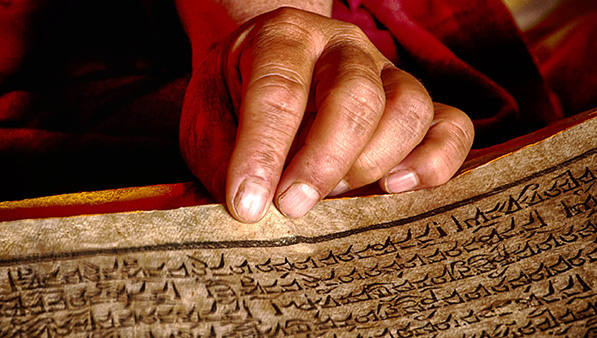 Close up image of a person’s hand holding a panel with written symbols on it