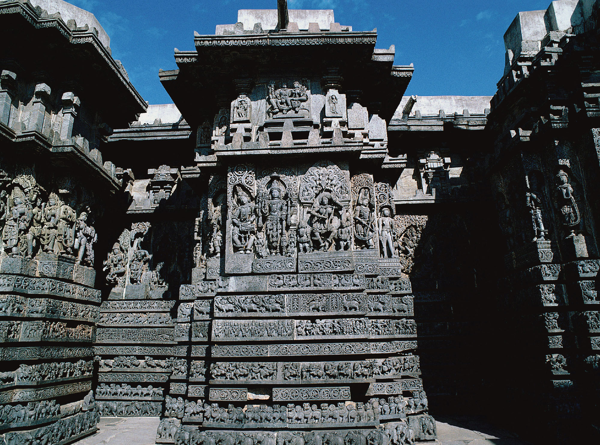 Photograph of an incredibly ornate Hindu temple. Figures are carved into stone, as well as many other symbols