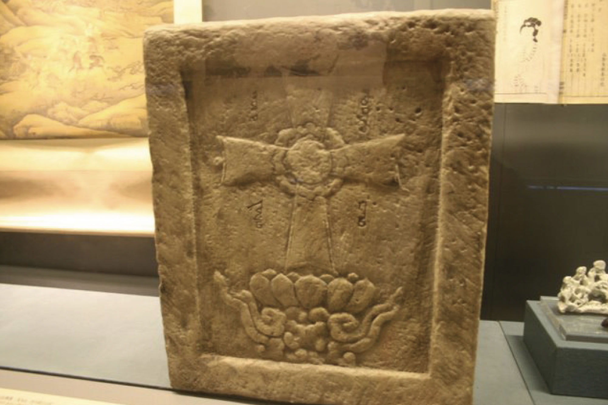 Photo of a stone carved with a cross-like symbol.