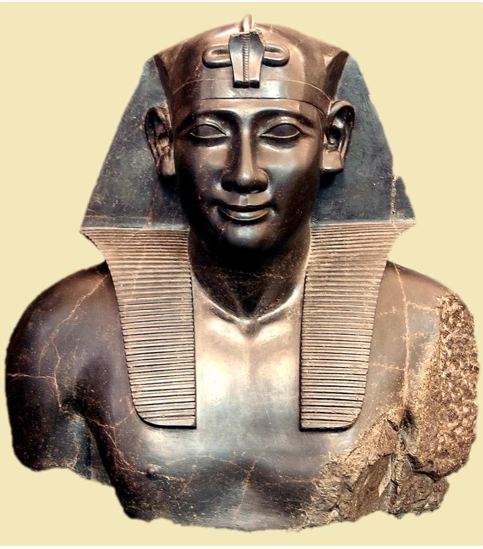 Ancient Egyptian statue of a pharaoh wearing a traditional nemes headdress, carved from dark stone with detailed facial features and partially damaged shoulders.