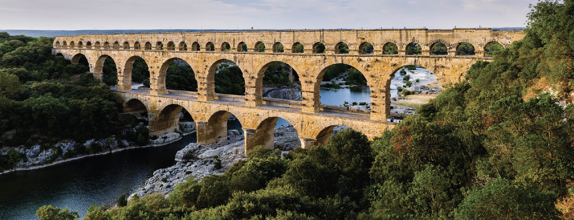 Picture of an aqueduct crossing a river valley: a bridge-like structure featuring many arches.