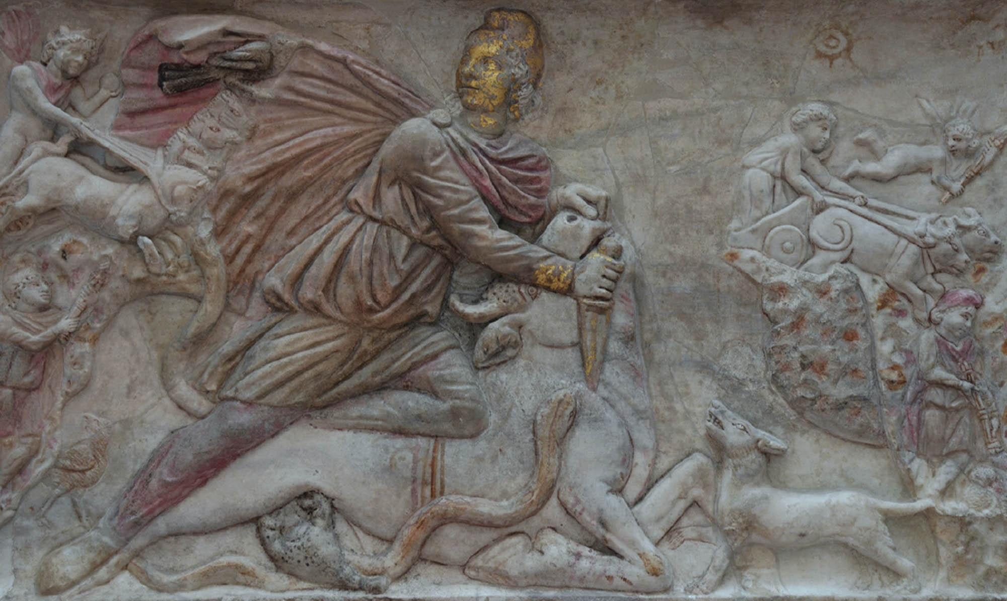 Stone carving depicts a scene of a man killing a bull with a dagger. He is looking behind him, where there is a man on horseback.