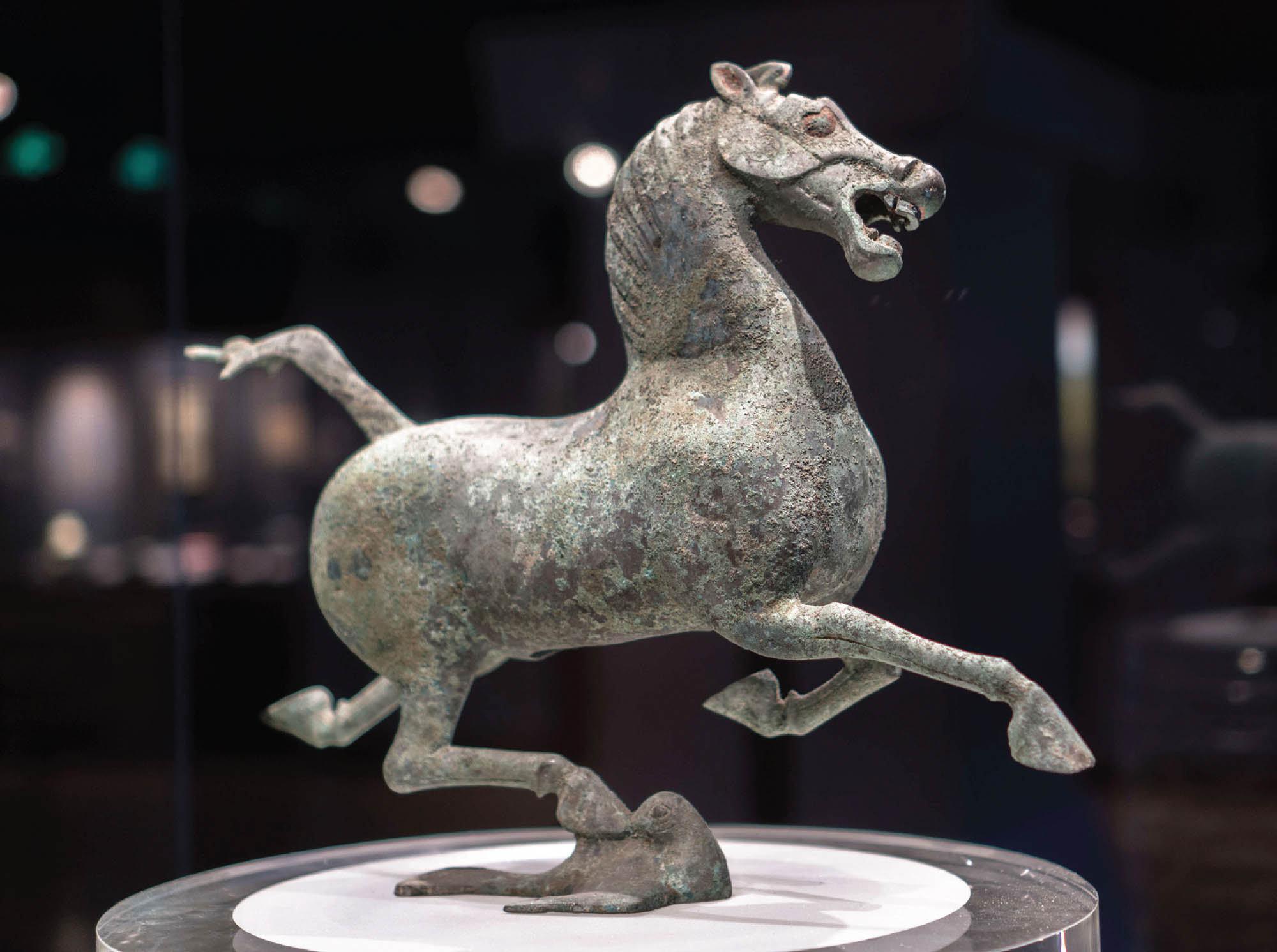 A sculpture of a horse. It is standing, balanced on one hoof, on the back of a bird.