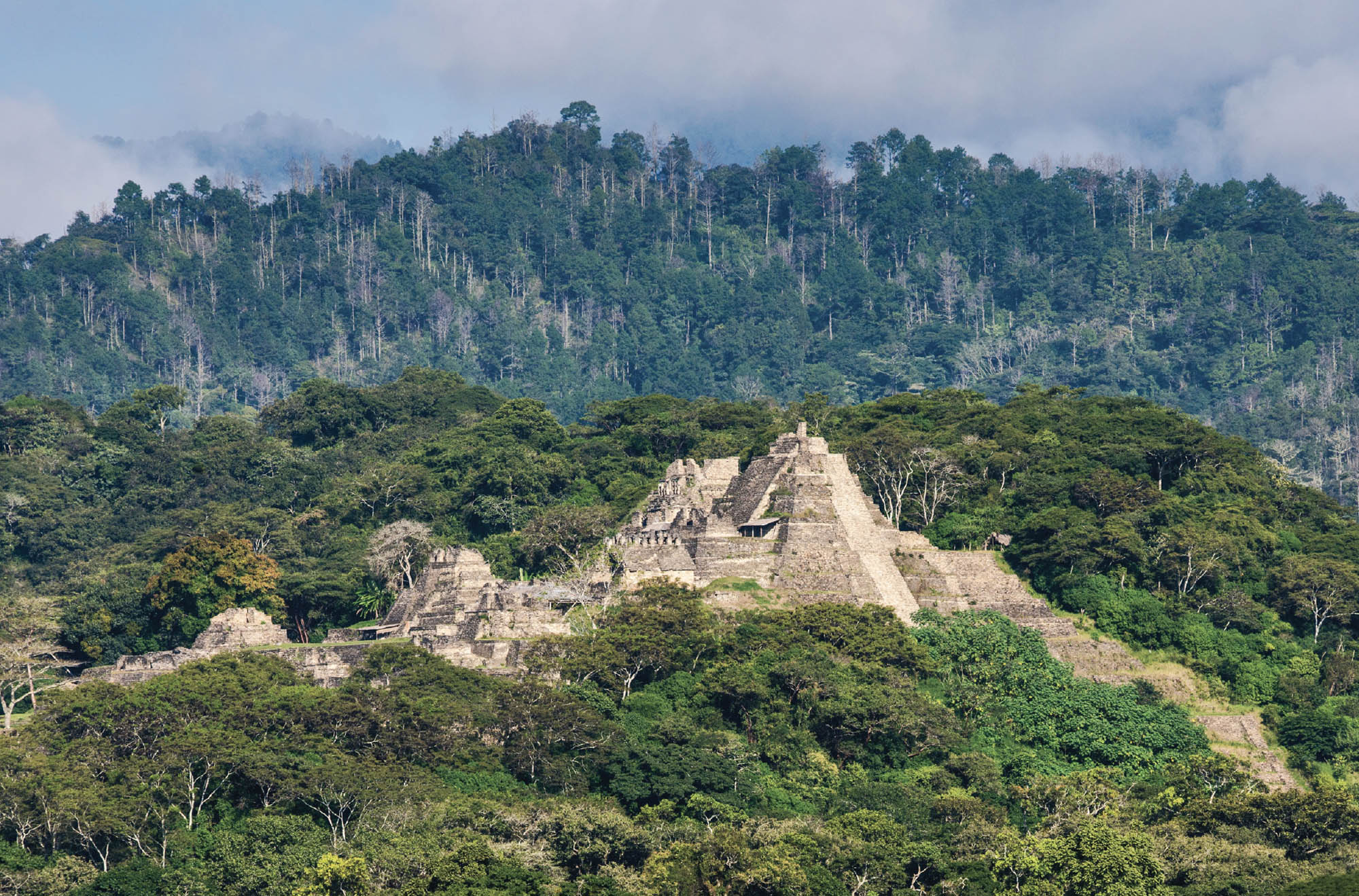 A photo of great stone structures on a green, tree covered hillside.