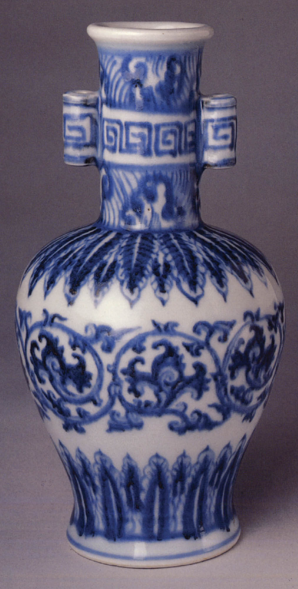 Photo of a ceramic vase. The vase is glazed in white and painted with an intricate design in blue.