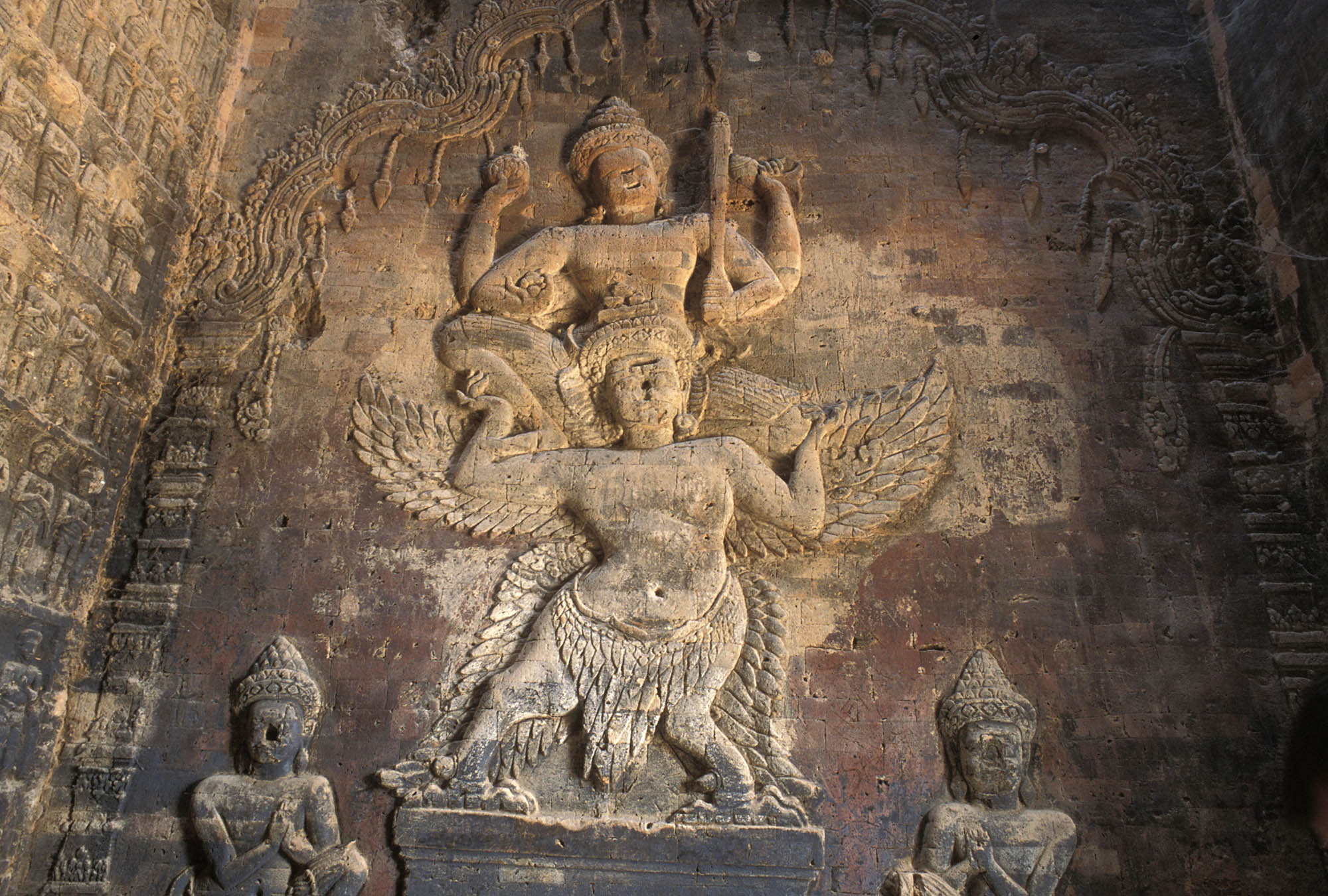 A stone carving of the god Vishnu standing on top of Garuda, his mount and guardian.