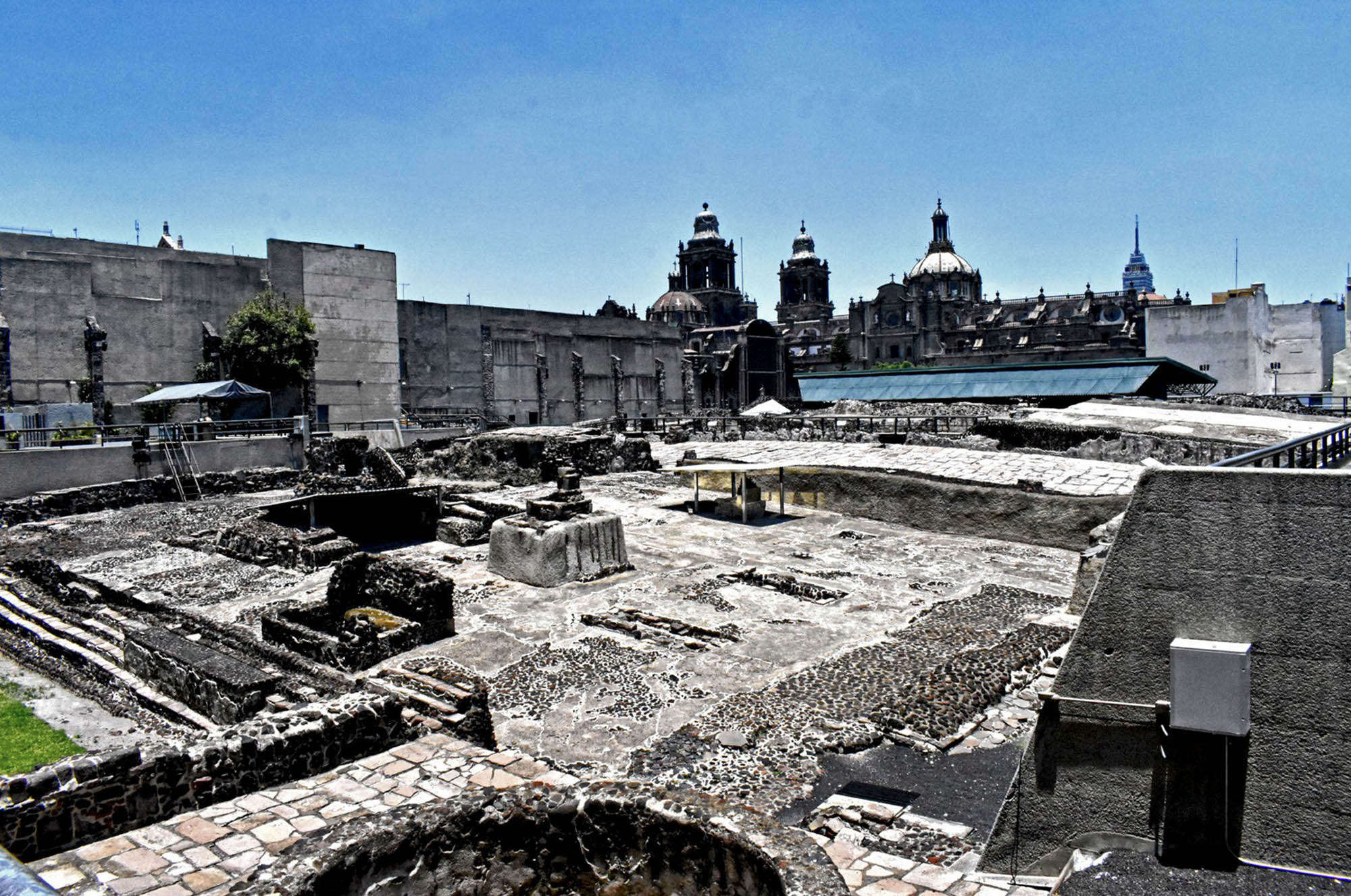 Photo of the ruins of Templo Mayor on a clear day with the Metropolitan Cathedral visible in the background.