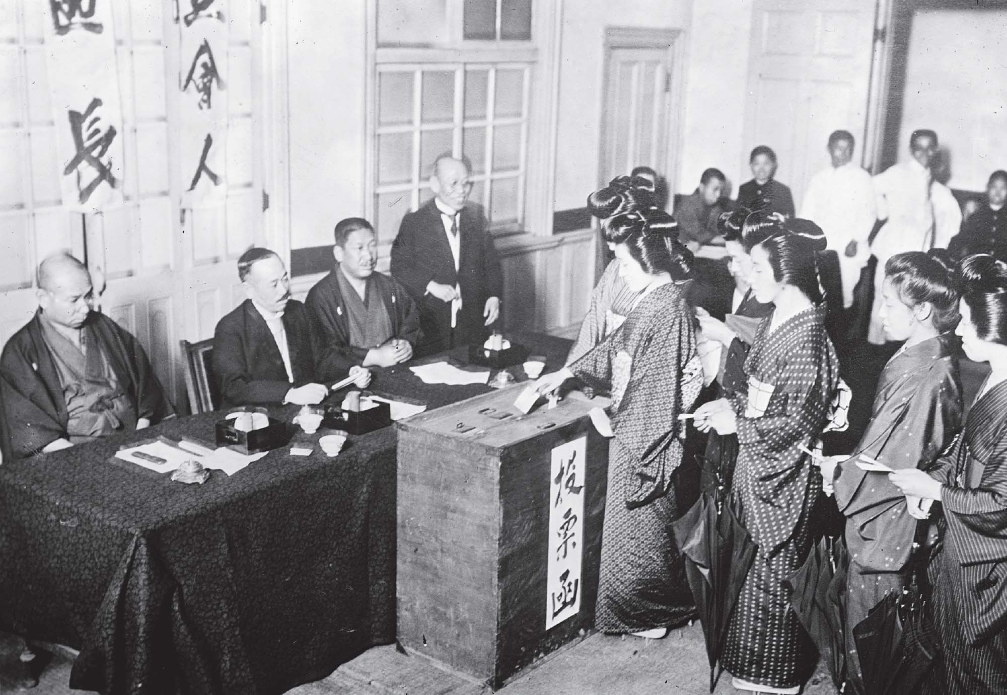 A group of women stand in line to cast their votes in a ballot box