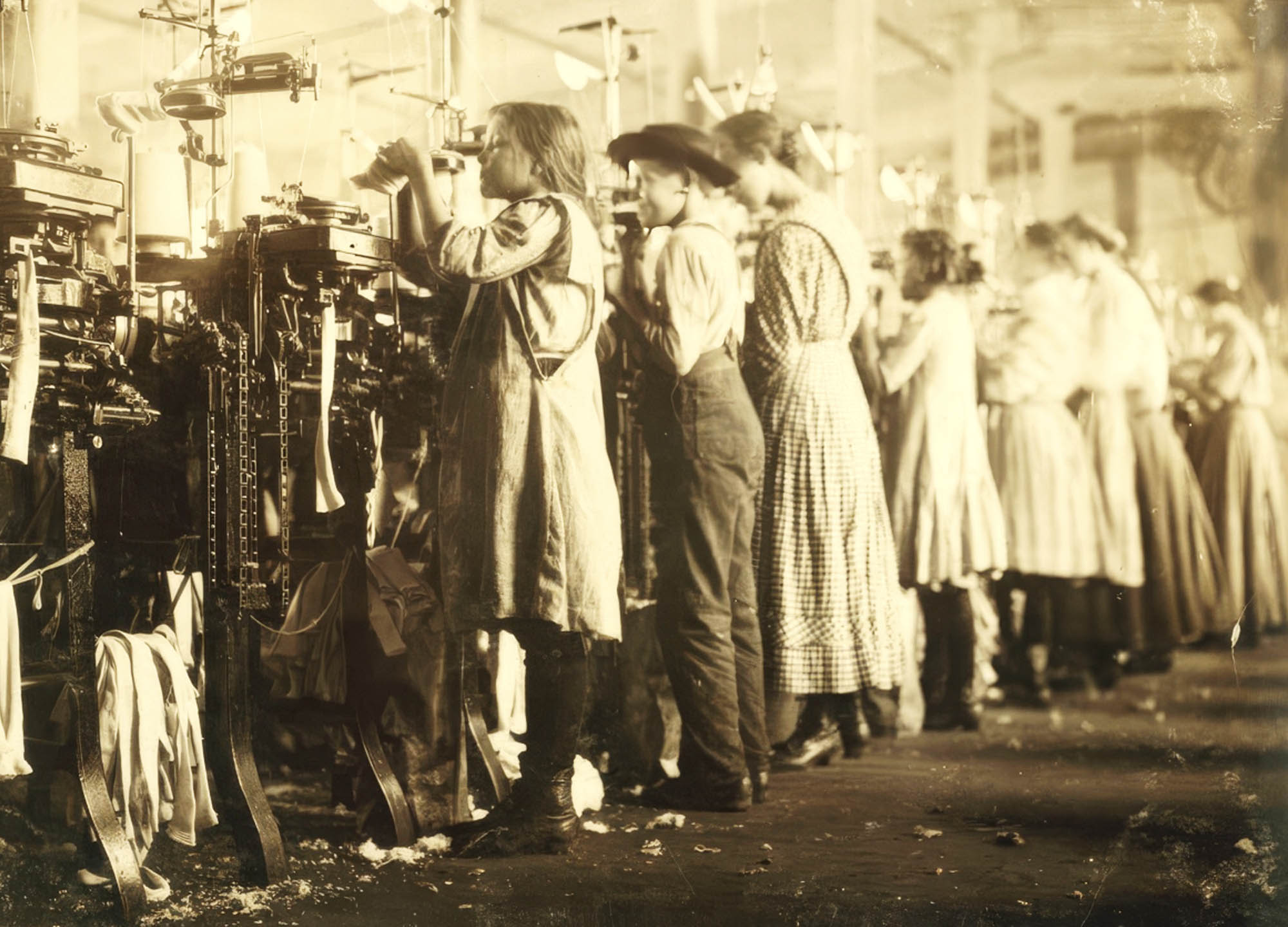 A photograph of young children workers operating machinery in a factory setting.