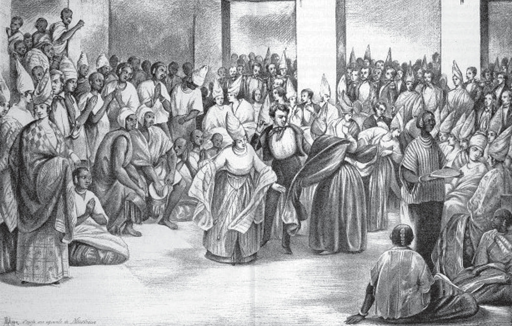 A large group of people in what appears to be a formal or ceremonial setting, the scene is in monochrome, many individuals are wearing distinctive conical hats or head coverings and are clustered around a central space.
