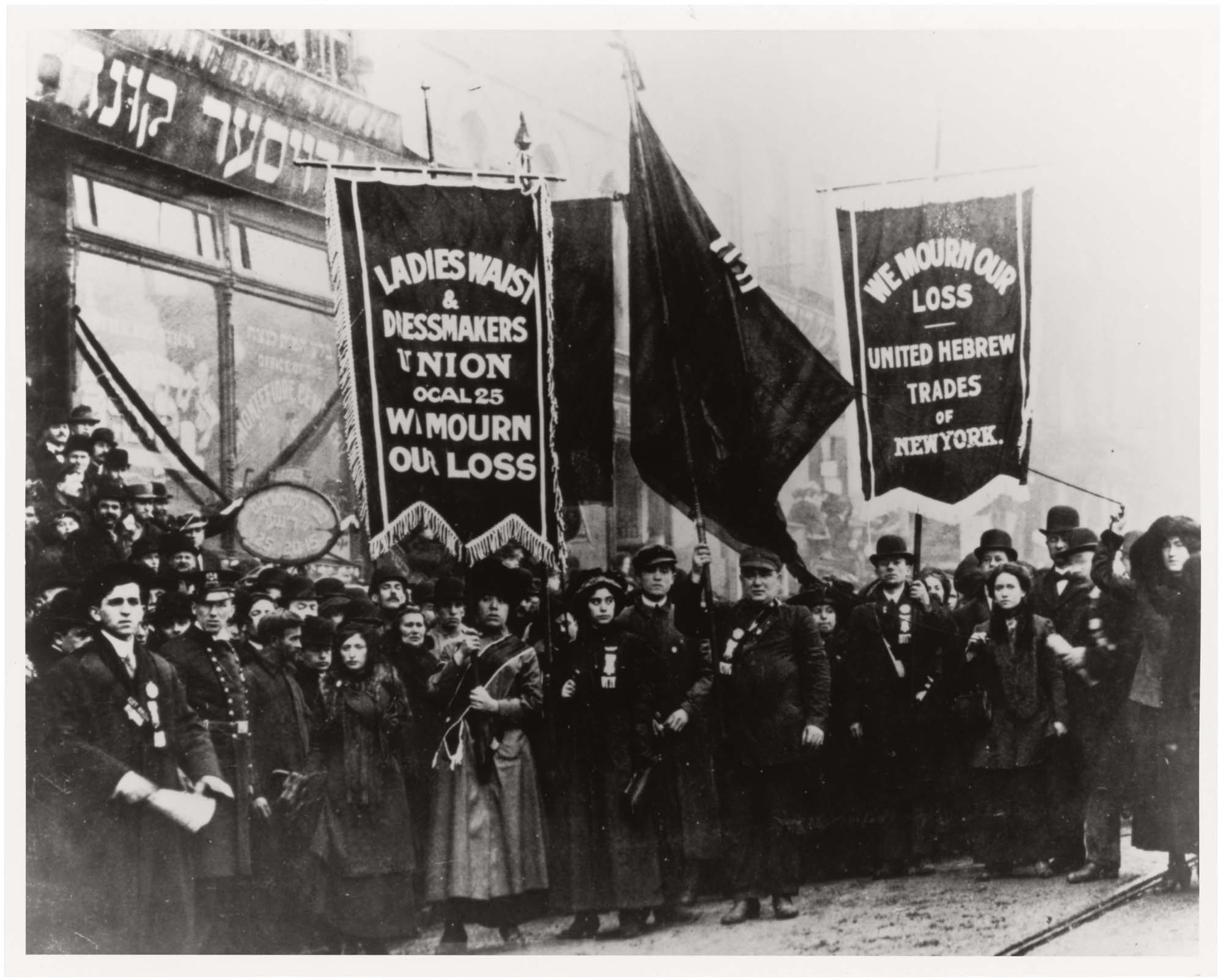 A photograph from a protest that took place after a terrible factory fire killed many workers. Signs read “we mourn our loss”.