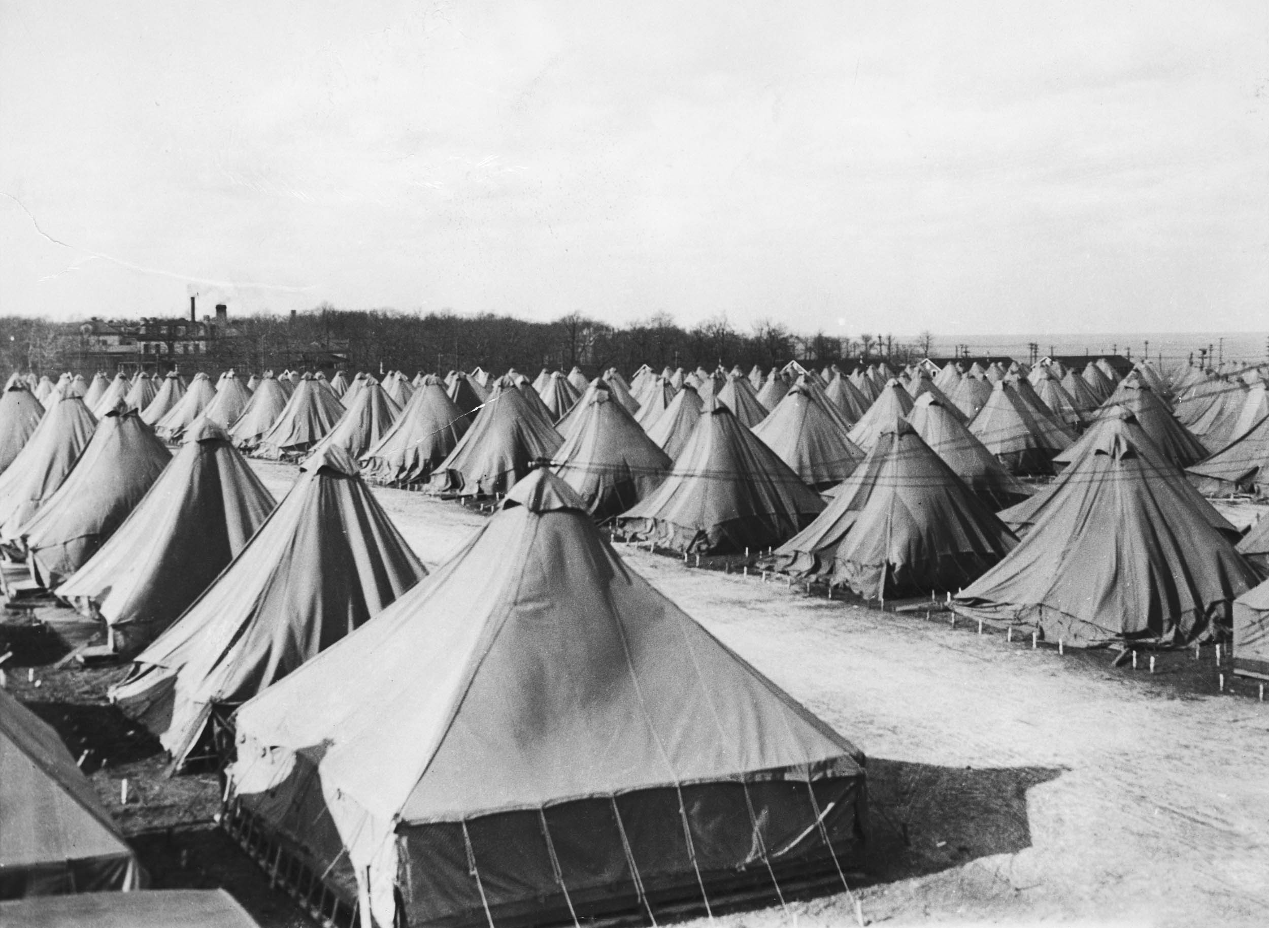 Black-and-white photo of rows of military-style canvas tents arranged in a grid.