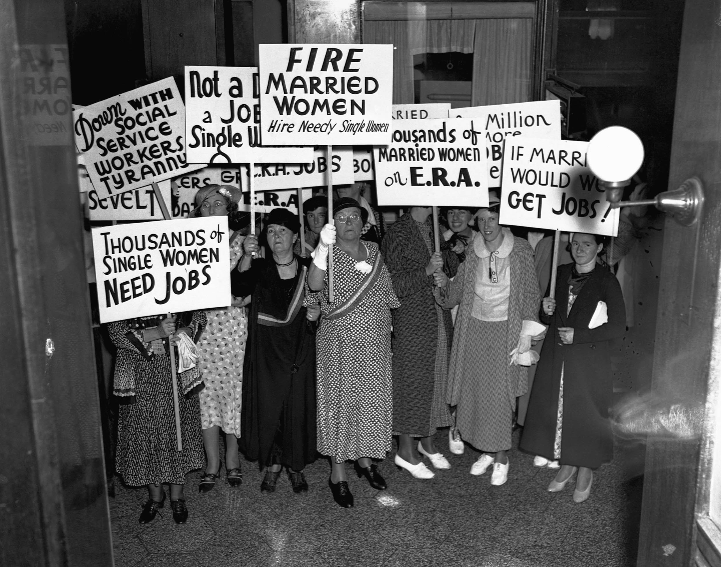 Black-and-white photo of women protestors holding signs demanding jobs for single women and calling for married women to be fired.