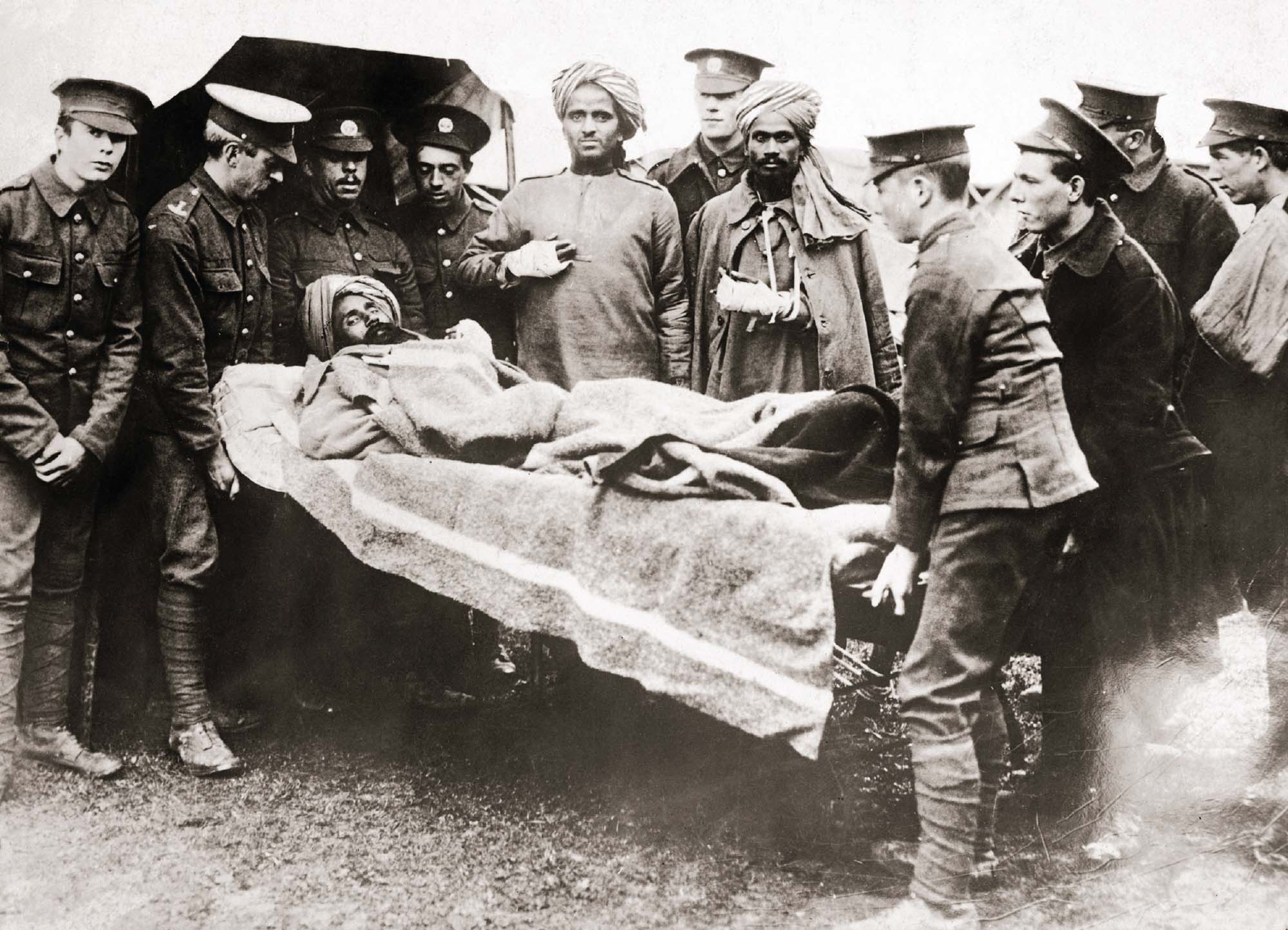 Black and white photograph of several men in army uniforms, carrying a man on a stretcher.