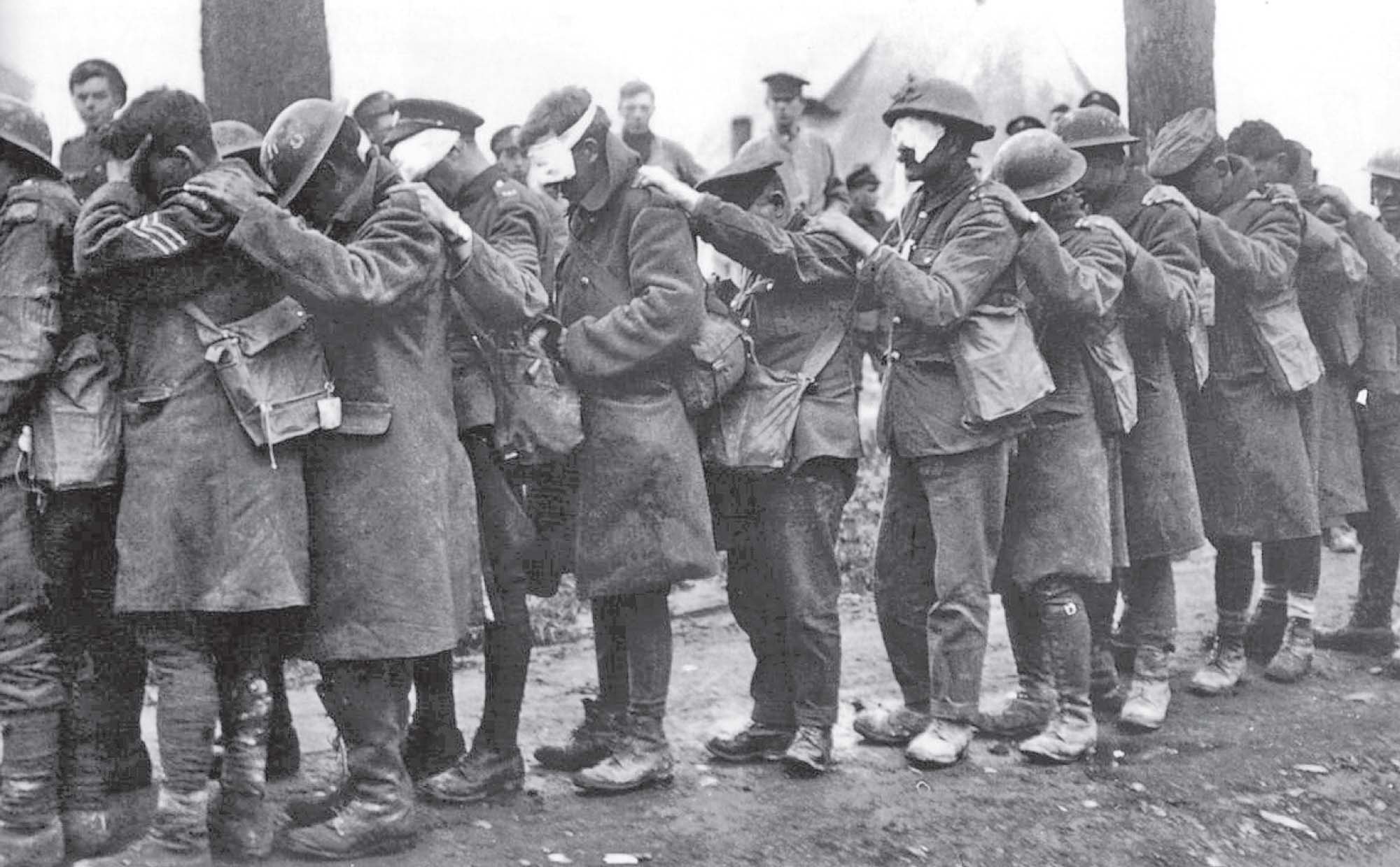 Photo of several soldiers, many with gauze covering their eyes and leaning into one another. They look to be in a great deal of pain.