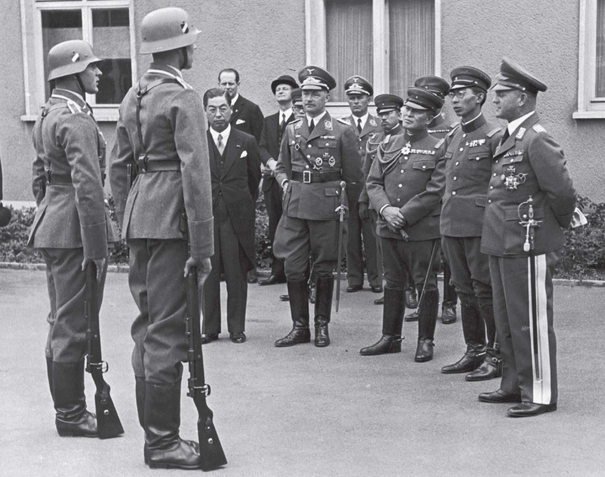 Photo of a small group of Japanese and German soldiers talking amongst each other outside of an airfield in Berlin.