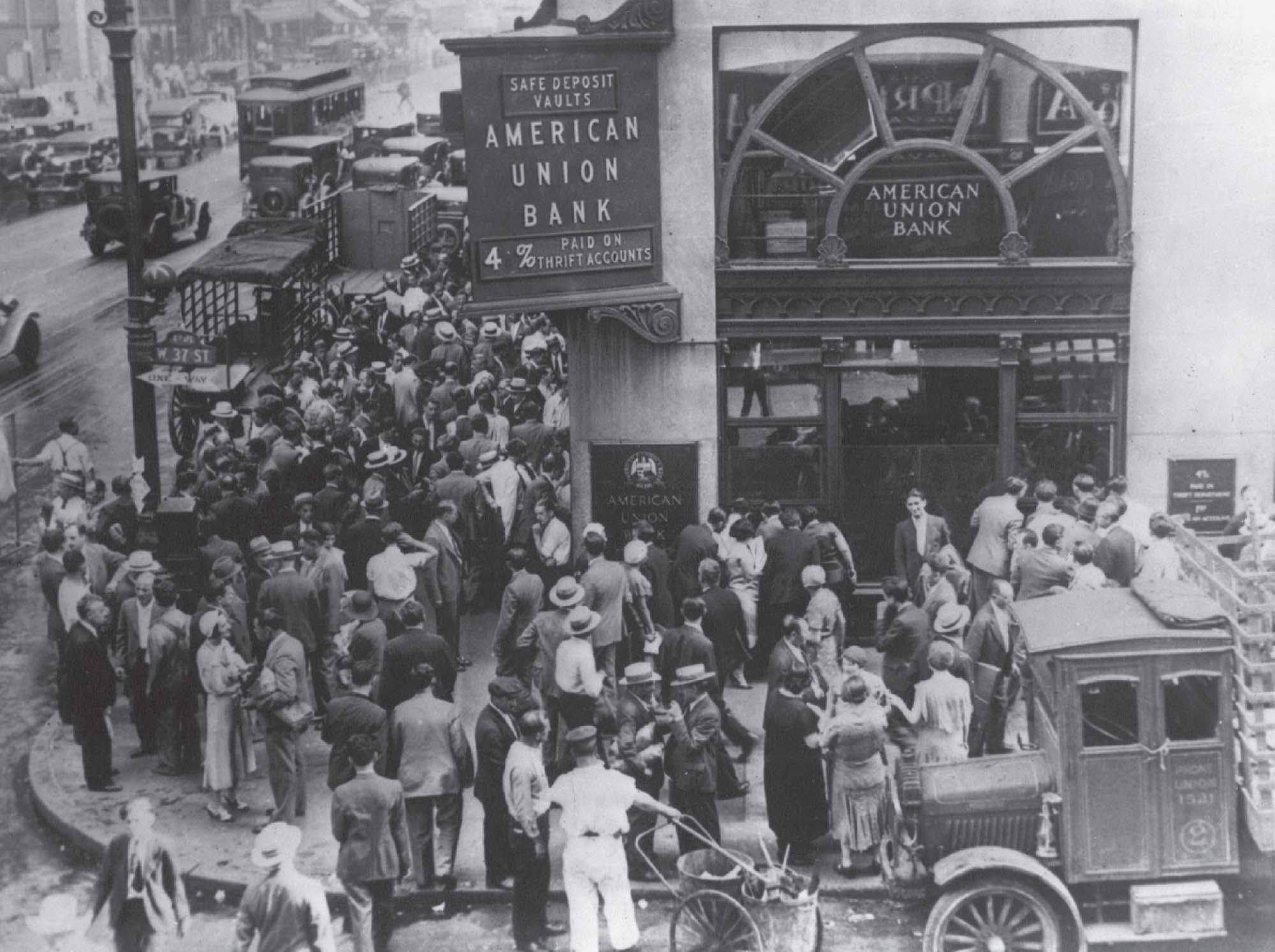 Photograph of a packed crowd standing on a city sidewalk, just outside of a bank.
