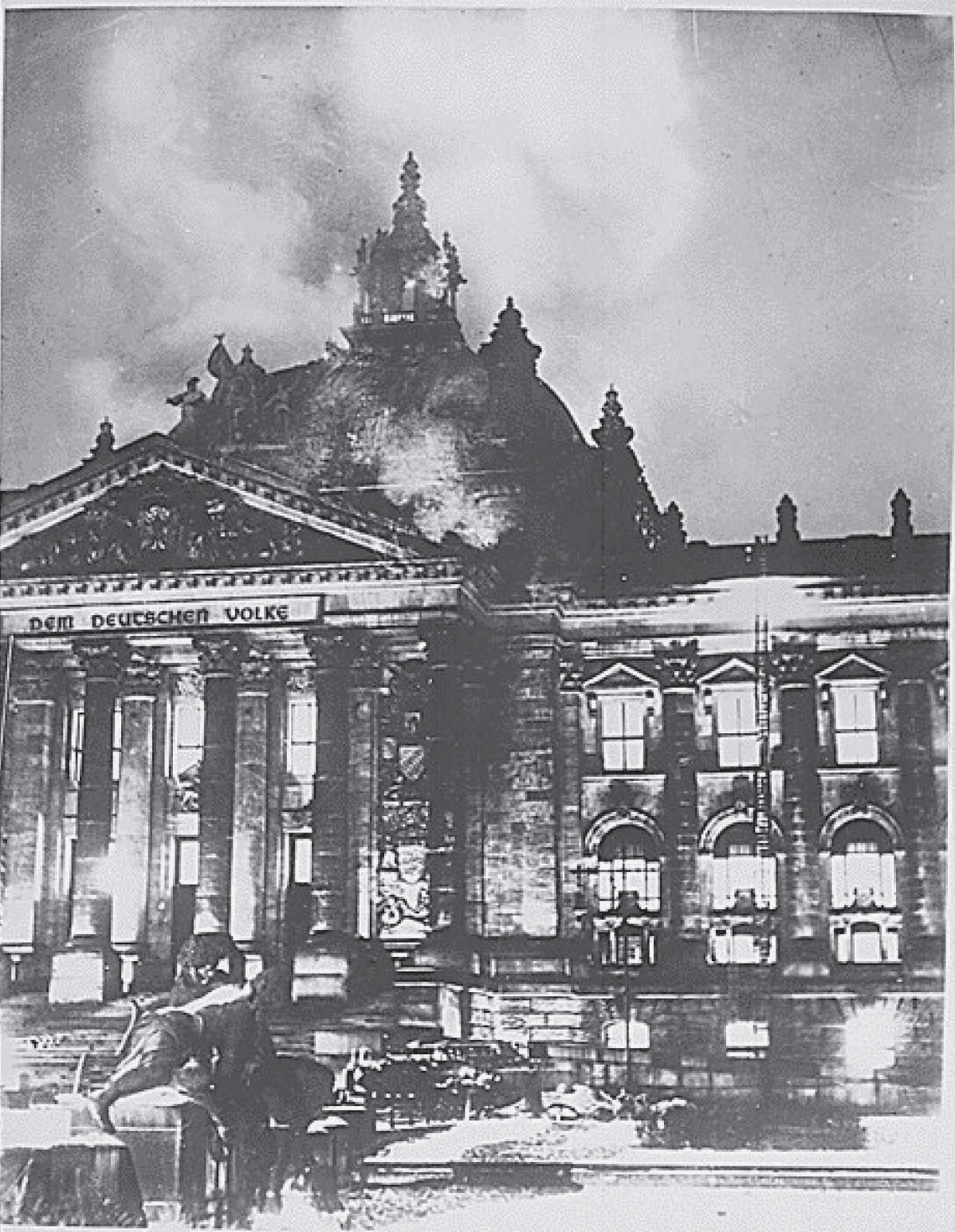 Photo of Berlin’s Reichstag building on fire. Smoke billows into the air as firefighters attempt to put the fire out.