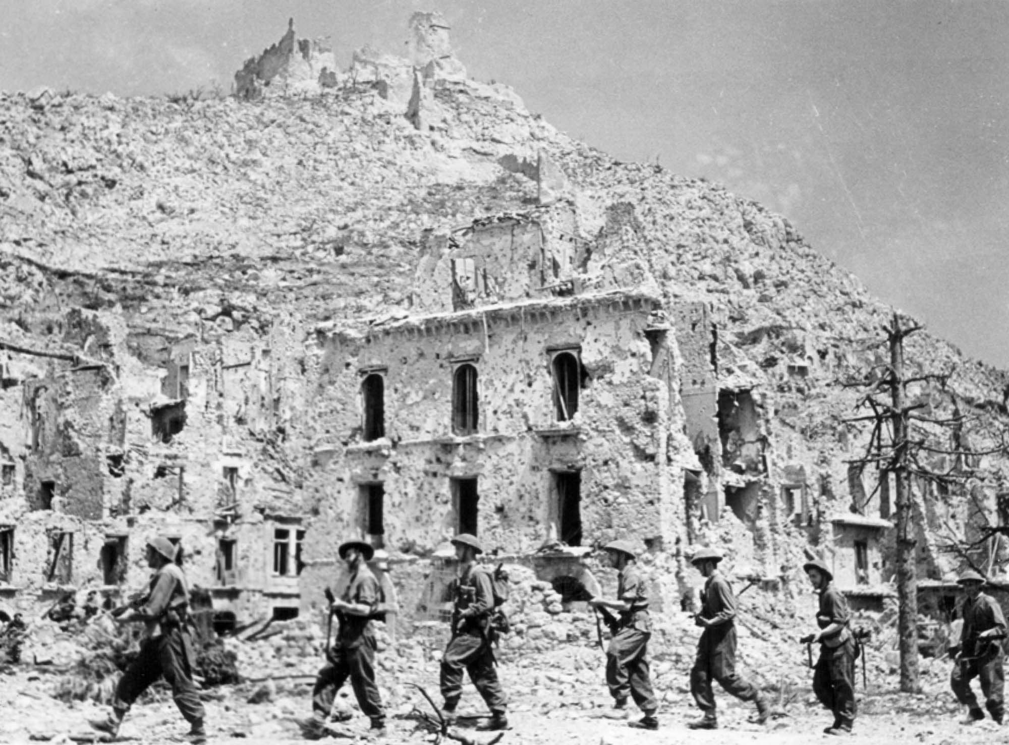 Allied troops marching past the ruins of a town, following the Battle of Monte Cassino during World War Two, May 1944.