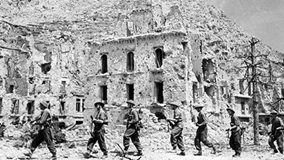 Allied troops marching past the ruins of a town, following the Battle of Monte Cassino during World War Two, May 1944.