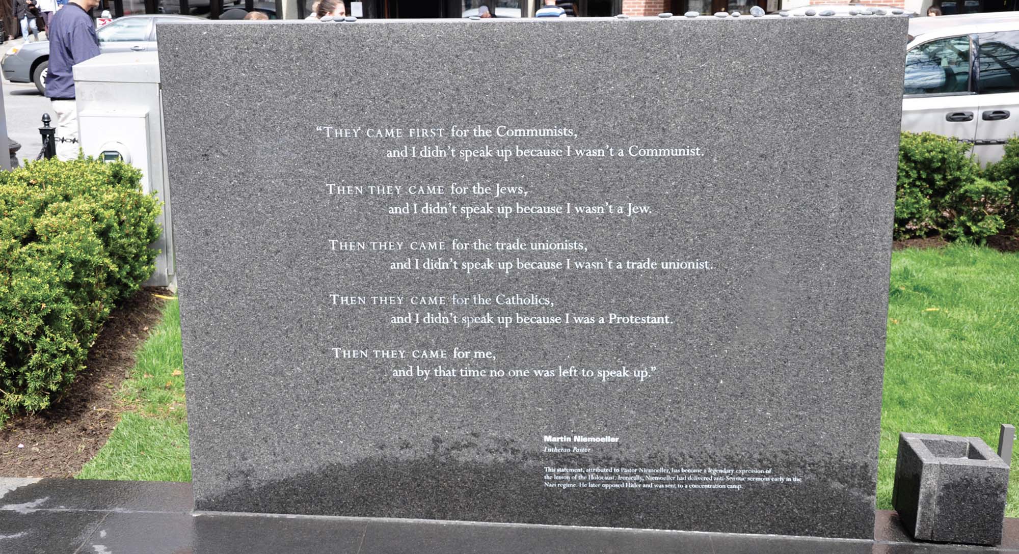 A large, grey memorial stone shows an engraving of a poem attributed to the German pastor Martin Niemöller. It was a confession he made after the war, and was subsequently translated in a poetic style. There are different versions, but the text here reads: “They came first for the Communists, and I didn’t speak up because I wasn’t a Communist / Then they came for the Jews, and I didn’t speak up because I wasn’t a Jew / Then they came for the trade unionists, and I didn’t speak up because I wasn’t a trade unionist / Then they came for the Catholics, and I didn’t speak up because I was a Protestant / Then they came for me, and by that time no one was left to speak up.”