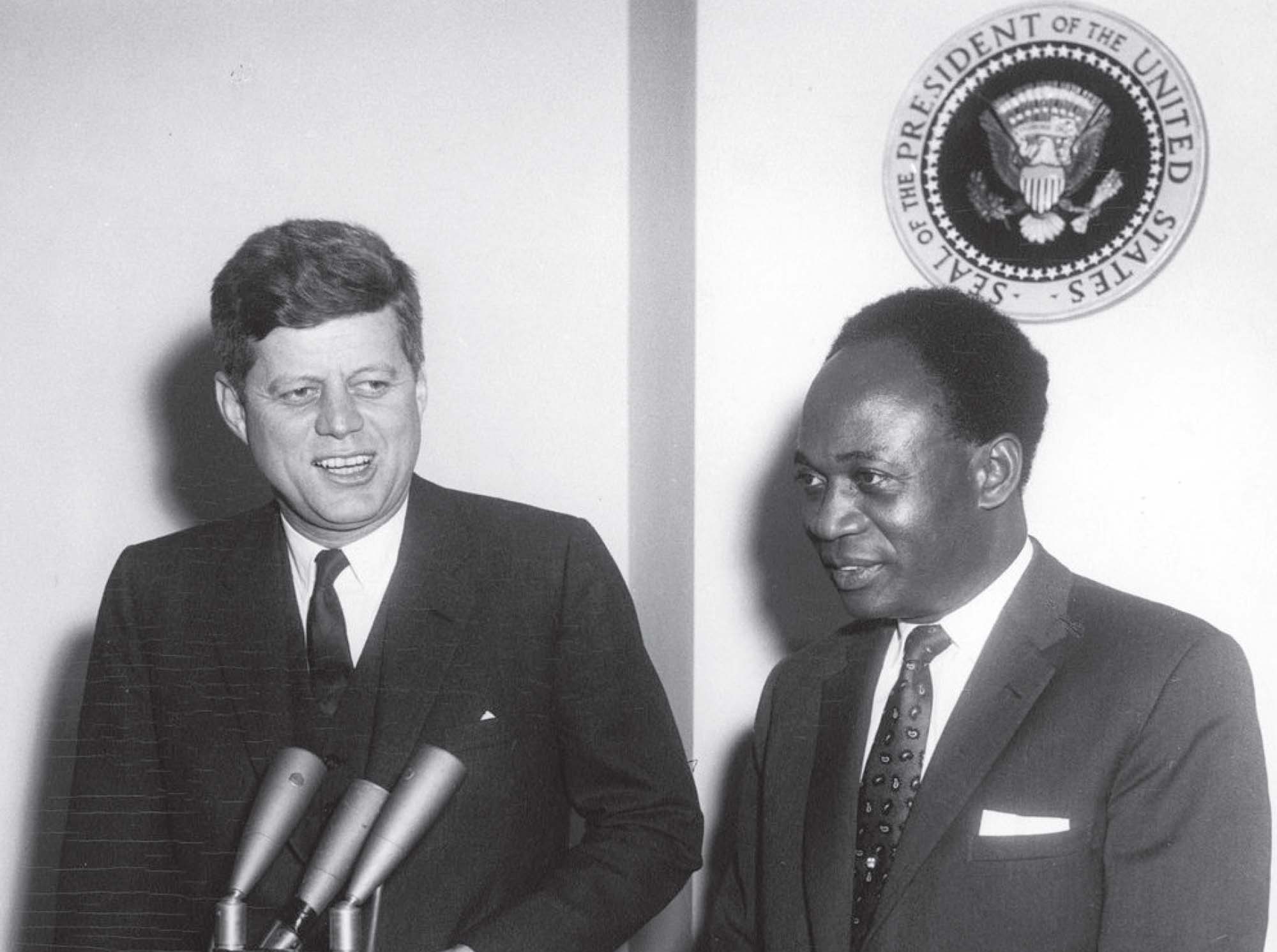 Two presidents, dressed in suits, stand next to each other at a podium in front of two microphones.
