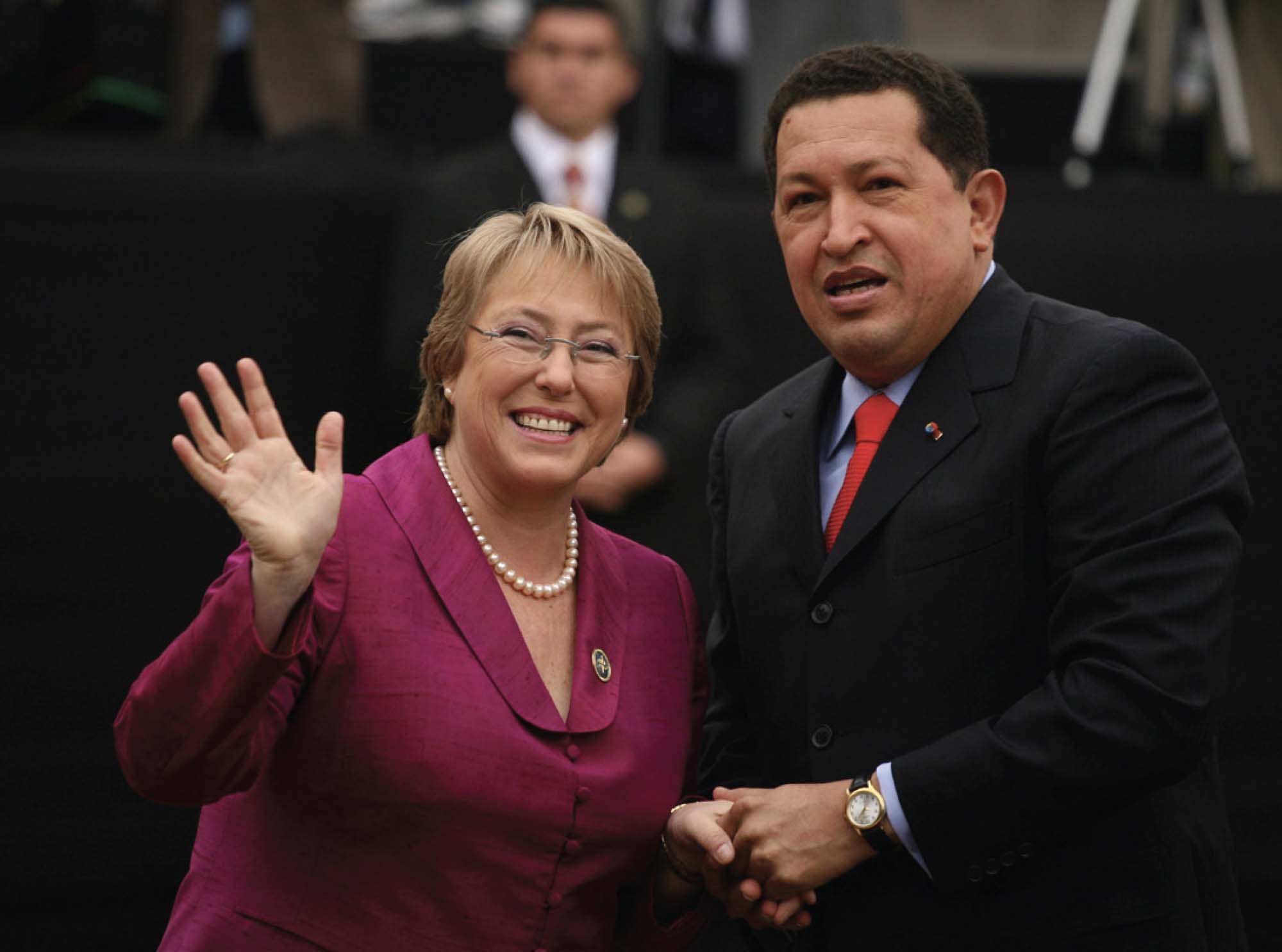 Two prominent politicians meeting, shaking hands, and waving.