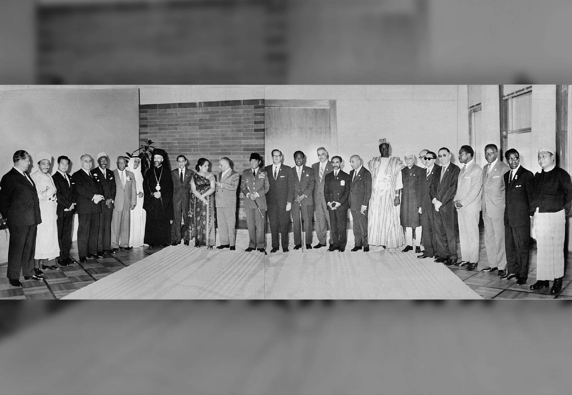 Black and white photo of delegates from unaligned nations standing along the back of a room for a photo.