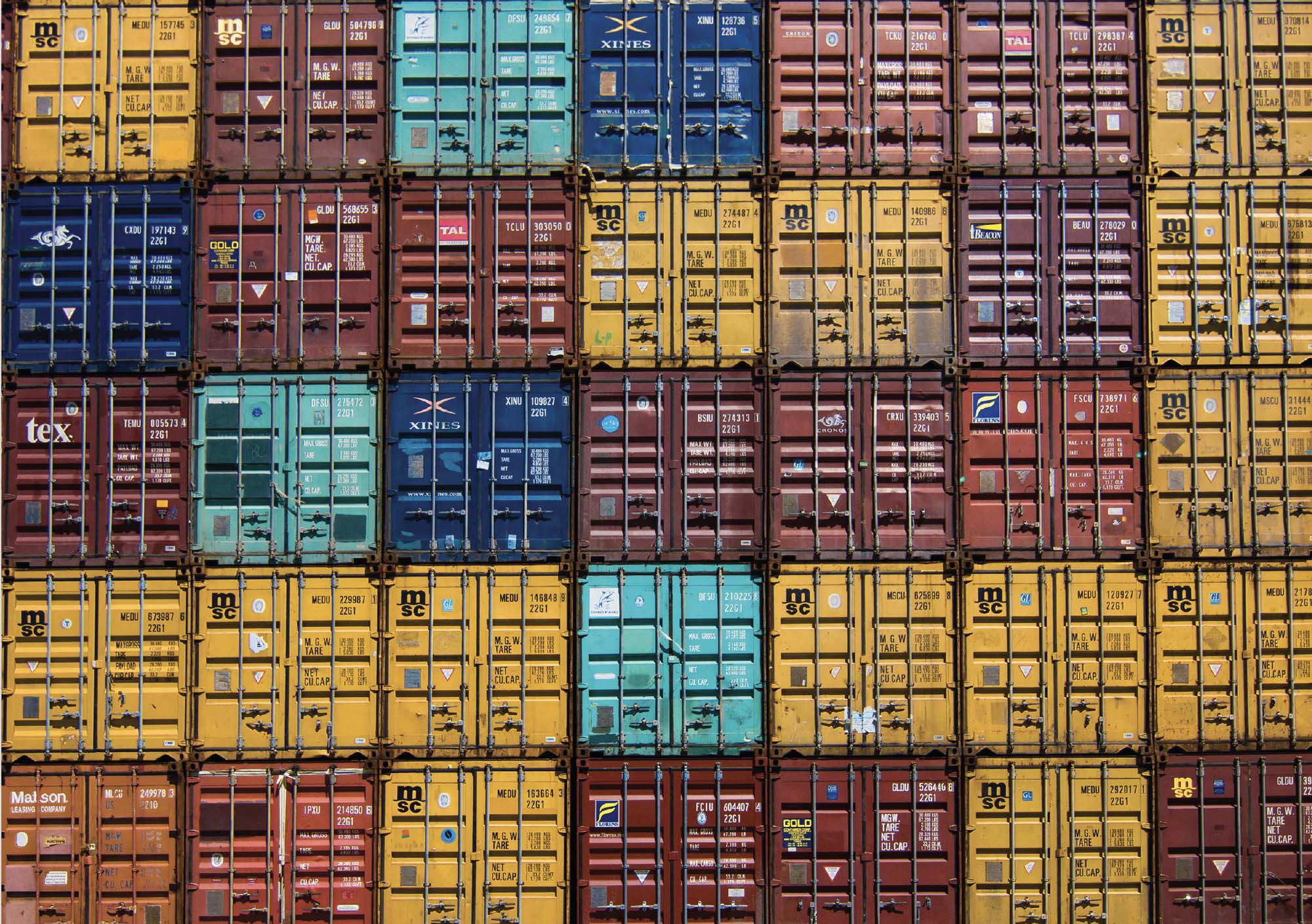 Photograph of shipping containers of different colors, stacked on top of one another like blocks.