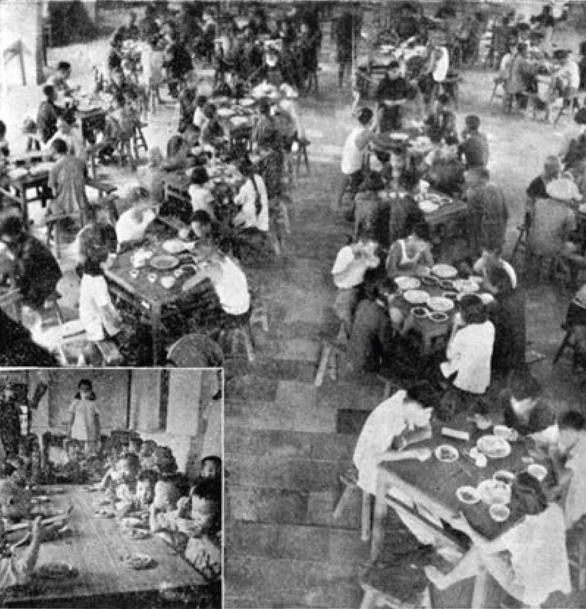 A photo of a crowded cafeteria, taken from above. Four-top tables are crowded with people that are eating their meals.