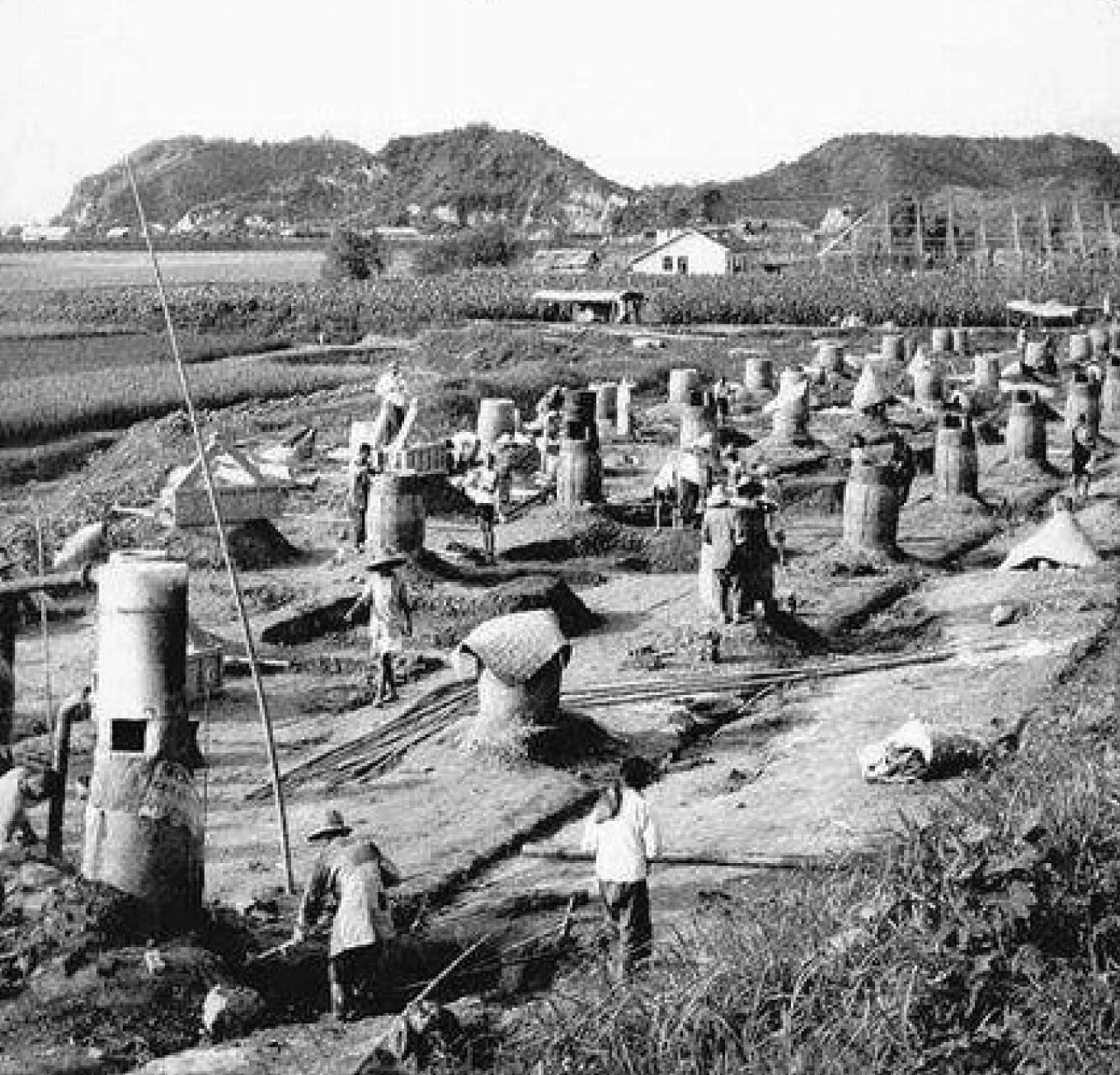 A photo shows several workers in a field, where many outdoor furnaces have been erected.