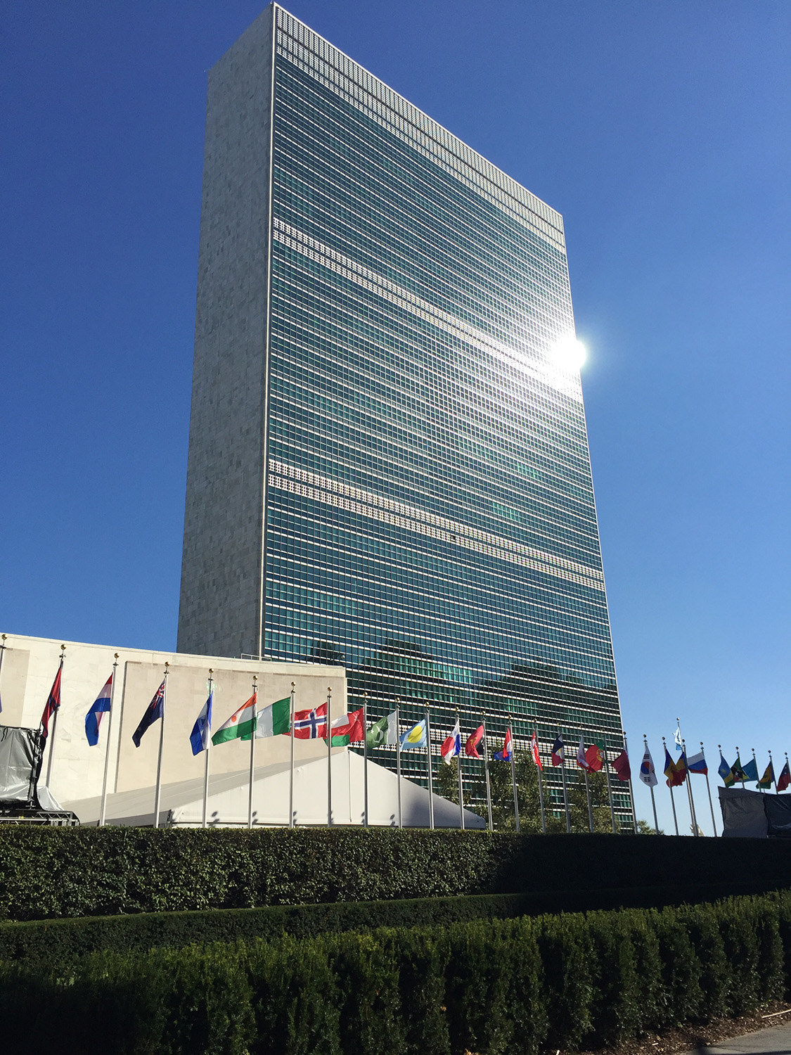 Monumental, multistorey office building with a row of country flags in the foreground.