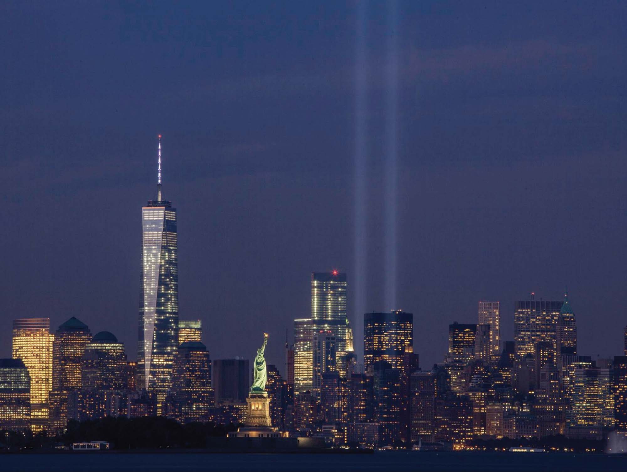 Photo of the New York City skyline post 9/11. Two light beams extend up into the sky where the World Trade Centers once were.