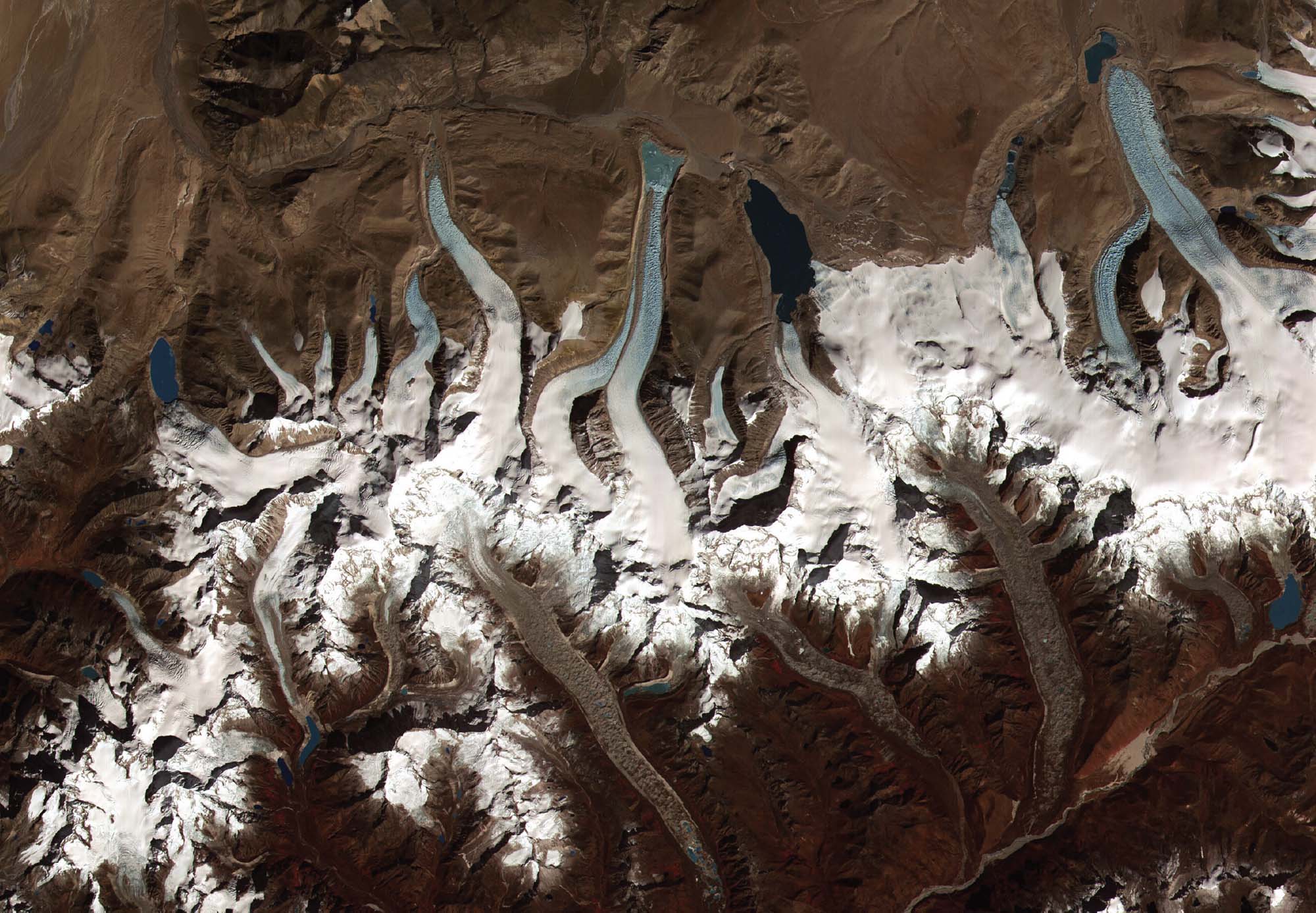 A birds-eye photograph shows great, snow-ice lakes on brown land.